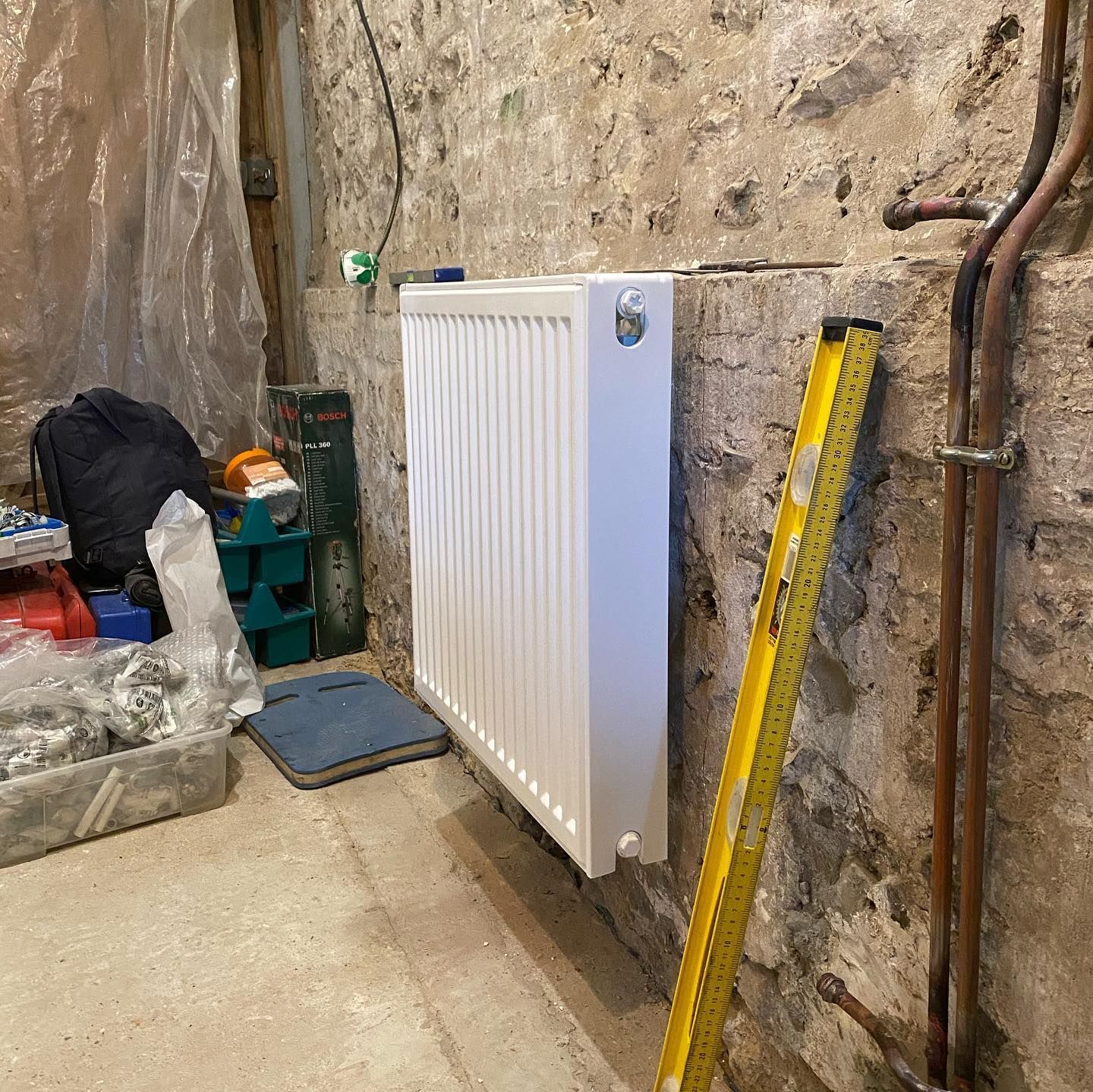 Un radiateur blanc horizontal à panneaux ajourés, fixé au mur sous une fenêtre.