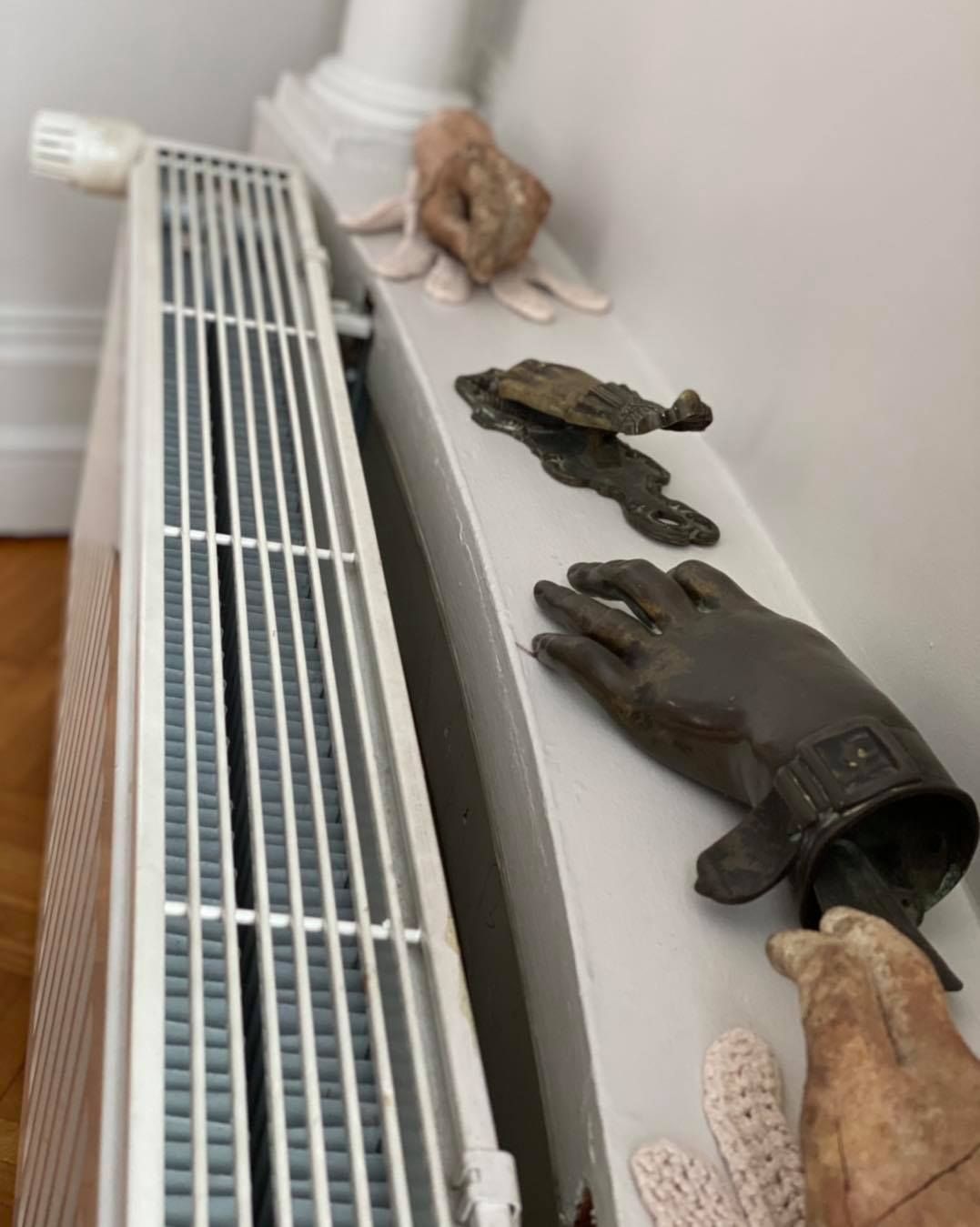 Un radiateur blanc sur un mur marron, avec un rideau transparent à rayures verticales à côté.