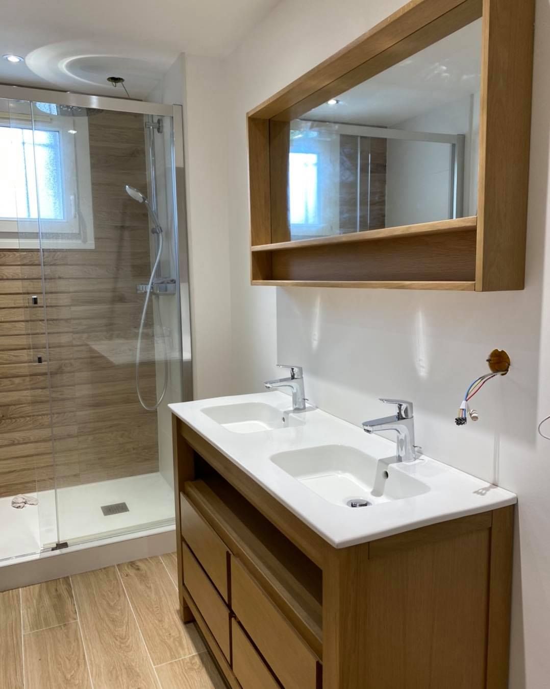 Une salle de bains moderne avec un meuble-lavabo, un plan de travail, un miroir rectangulaire et une douche vitrée.