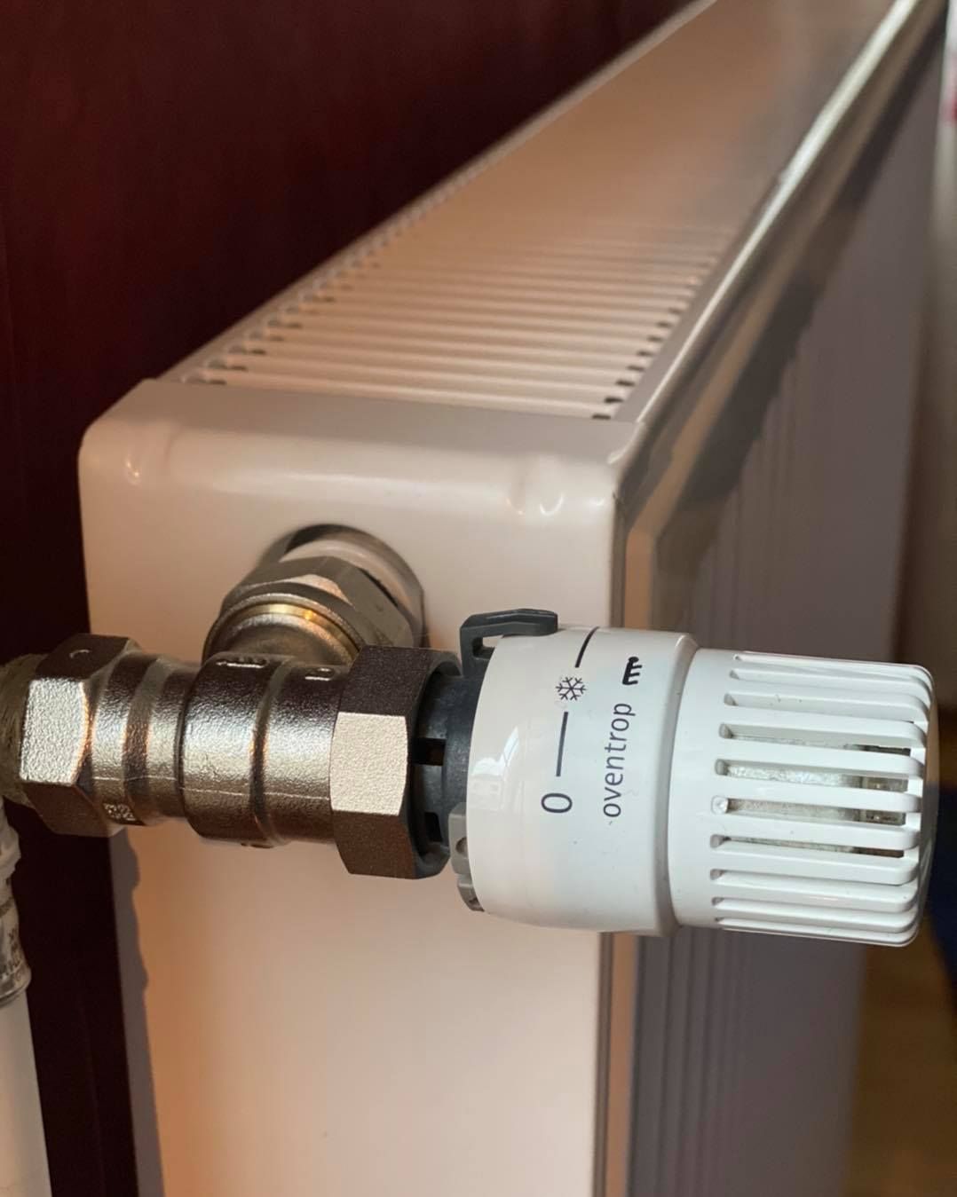 Une vanne thermostatique blanche de radiateur réglée sur la position hors gel sur un appareil de chauffage domestique.
