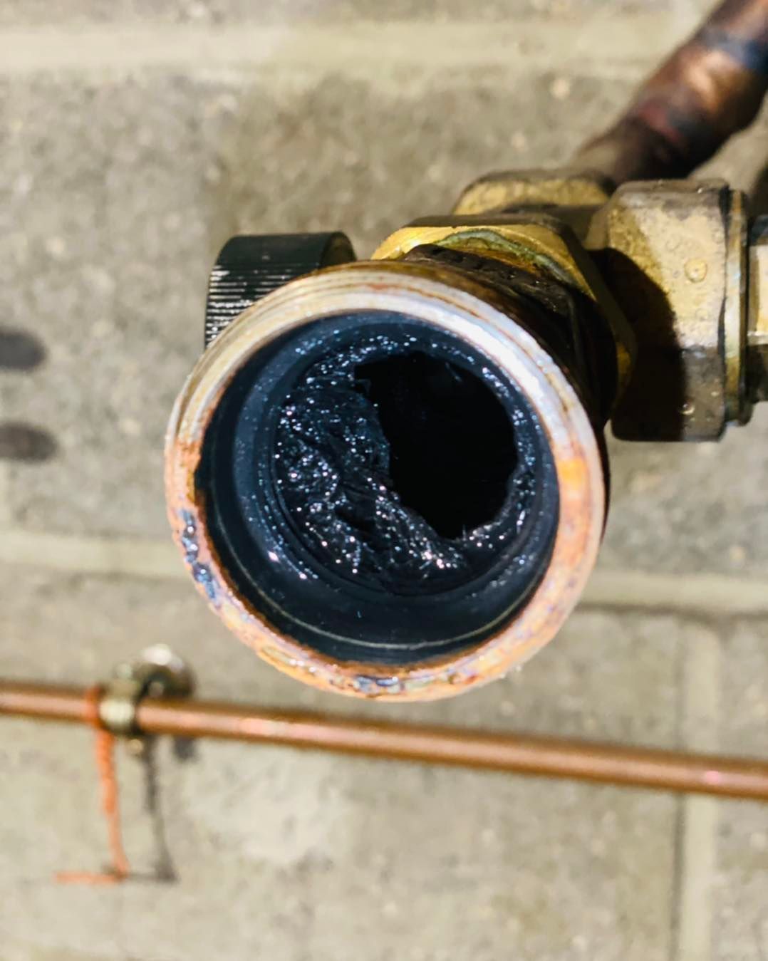 Gros plan sur l'intérieur d'un tuyau de plomberie métallique rempli de boue.