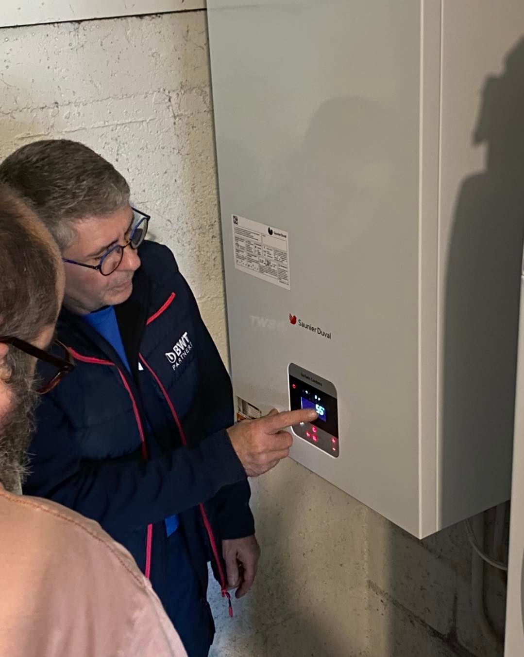 Un plombier désigne le panneau de commande numérique d'un appareil de chauffage mural.