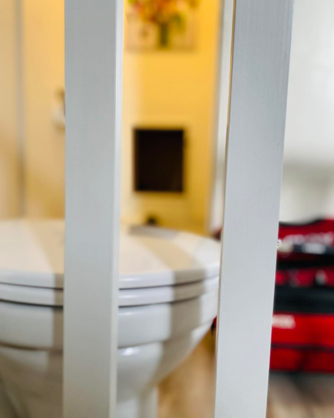 On aperçoit des toilettes blanches à travers les lattes verticales d'une cloison en bois.