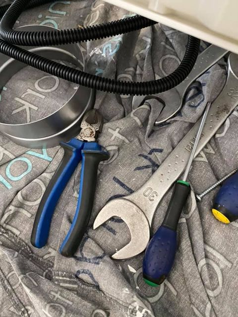 Un ensemble d'outils comprenant une pince, une grande clé et des tournevis, posés sur un tissu gris à motifs.