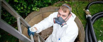 Person im Schutzanzug reinigt einen Tank