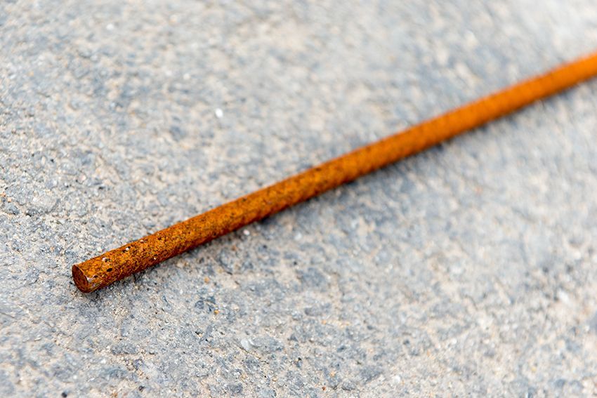 Tige métallique orange rouille sur une surface texturée gris clair