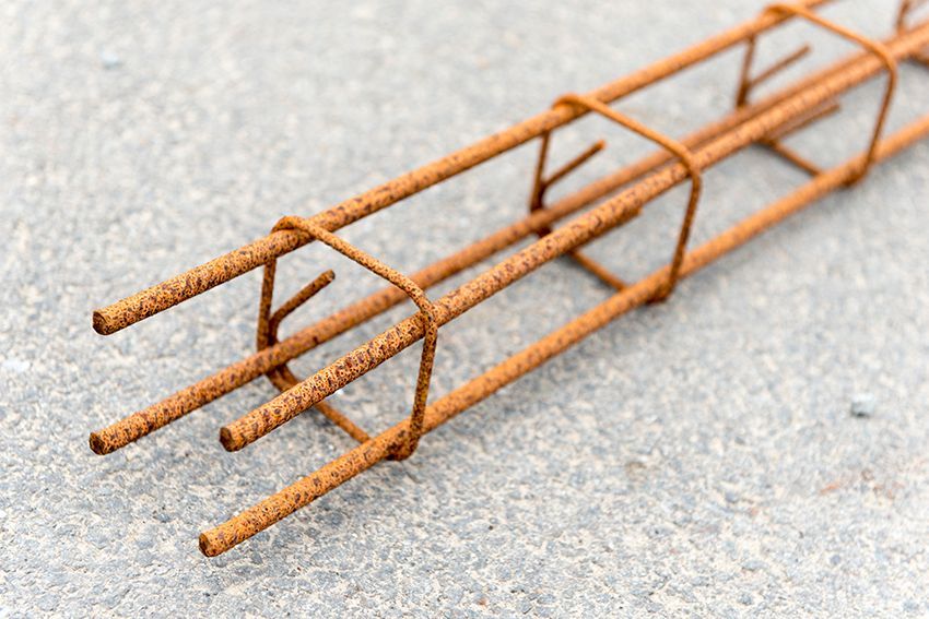 Cage d'armature couleur rouille reposant sur une surface en béton gris