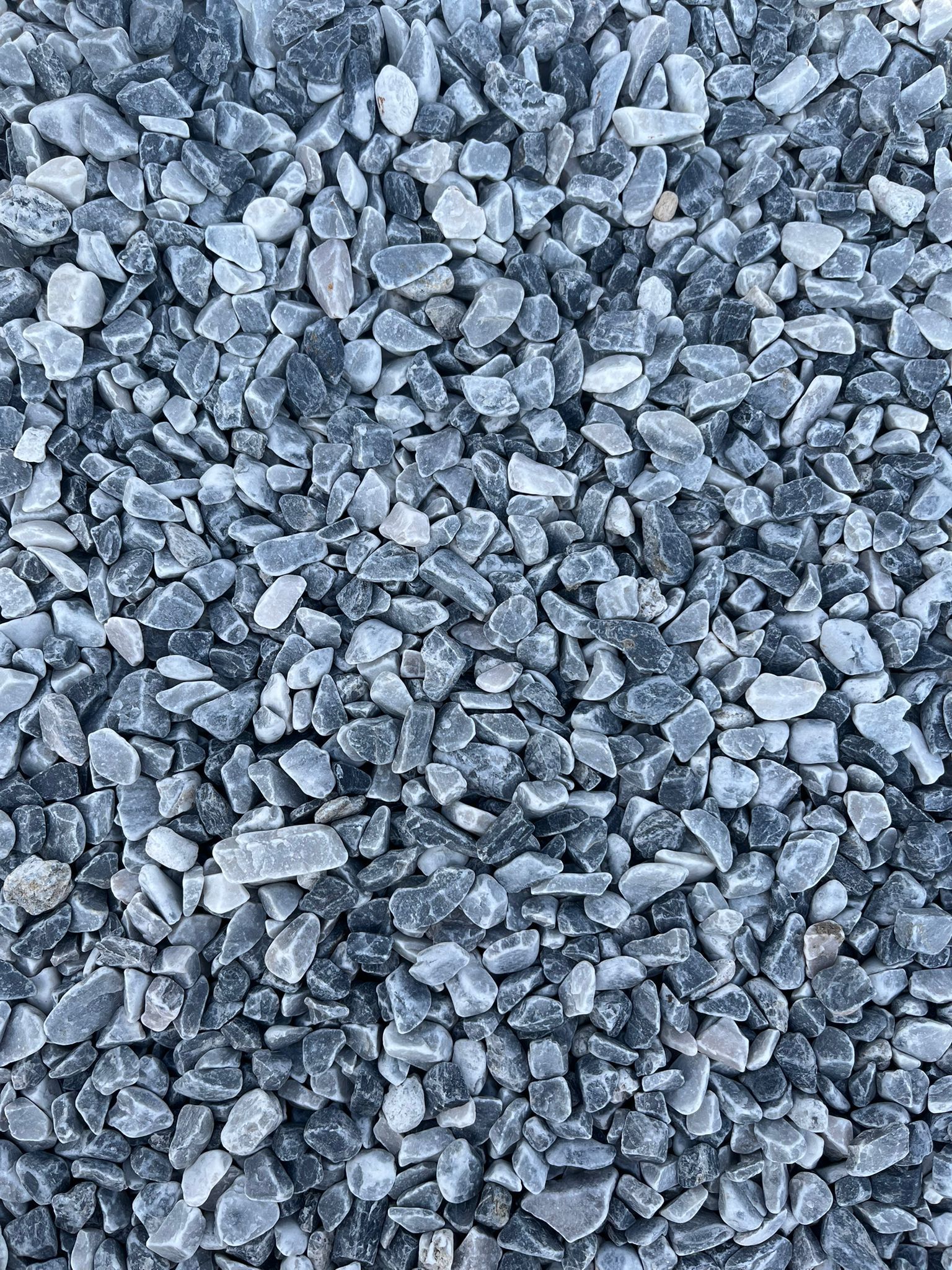 Gros plan sur de petits cailloux gris concassés ou du gravier remplissant le cadre.