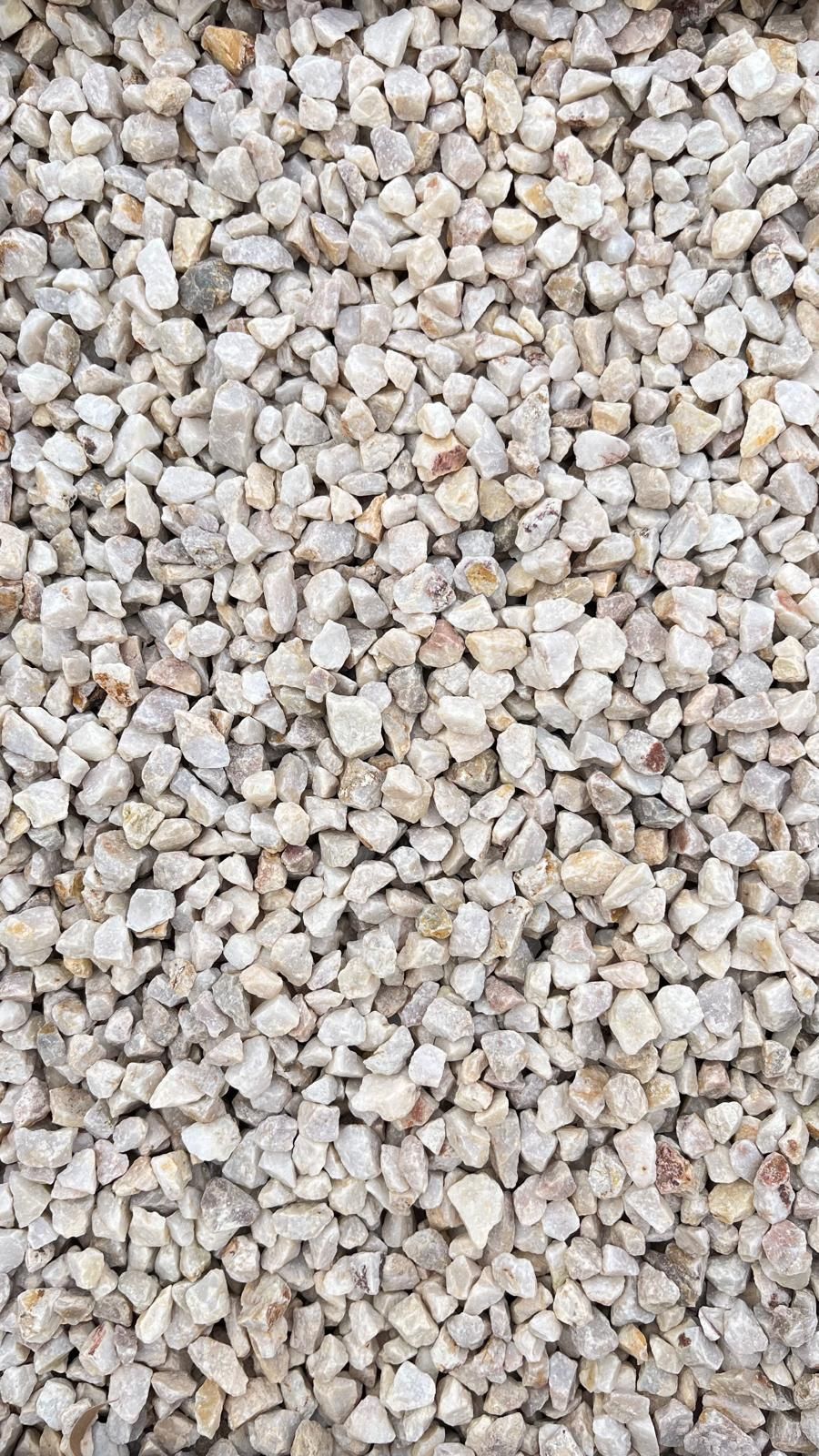 Gros plan sur de petits cailloux beige clair et gris remplissant le cadre