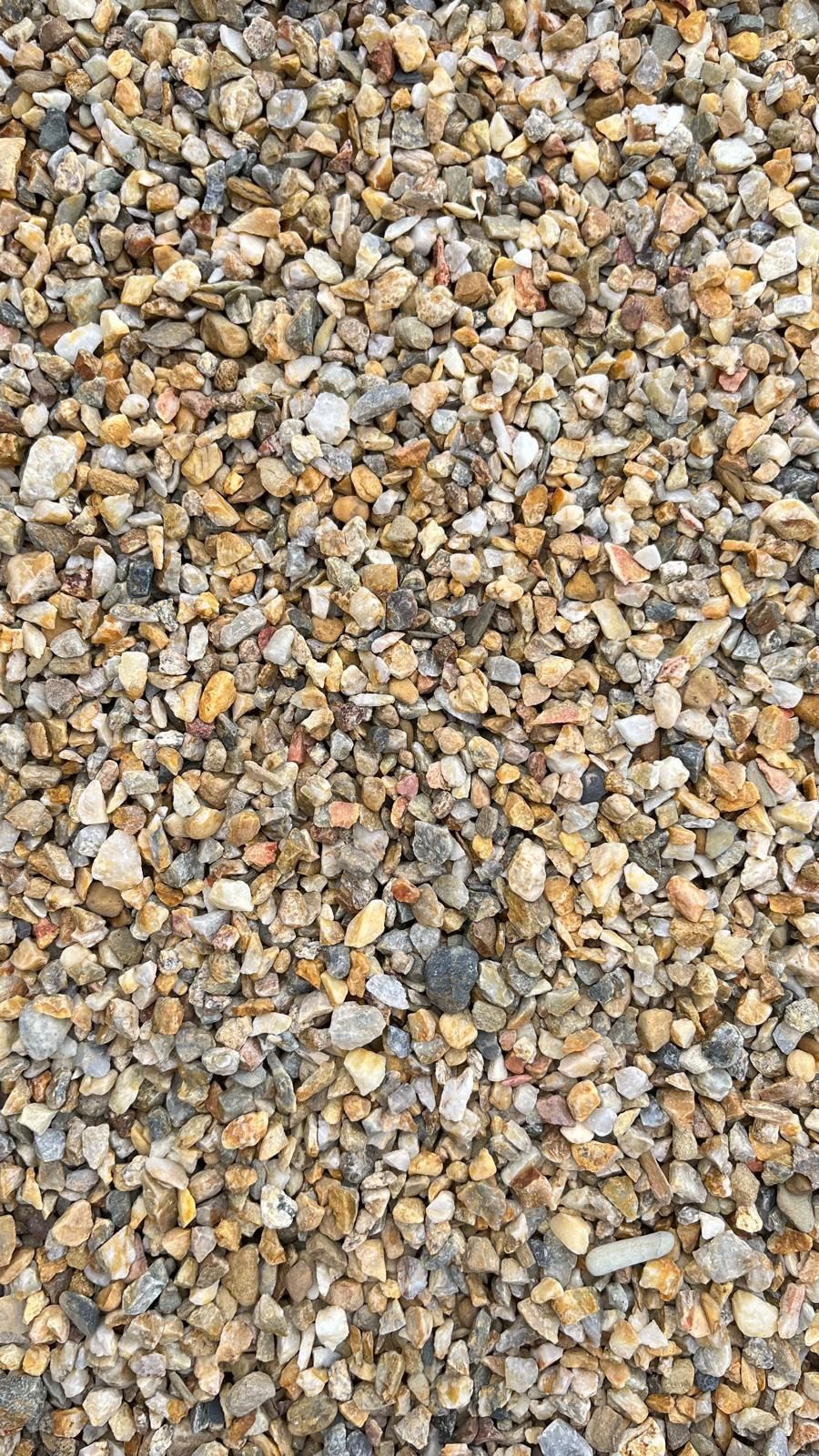 Gros plan sur un mélange de petits graviers dans des tons beiges, gris et brun clair.