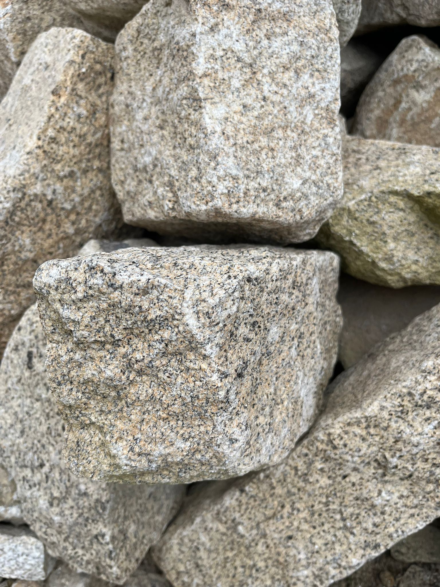Tas de gravier gris clair et beige avec des pierres rugueuses et anguleuses.
