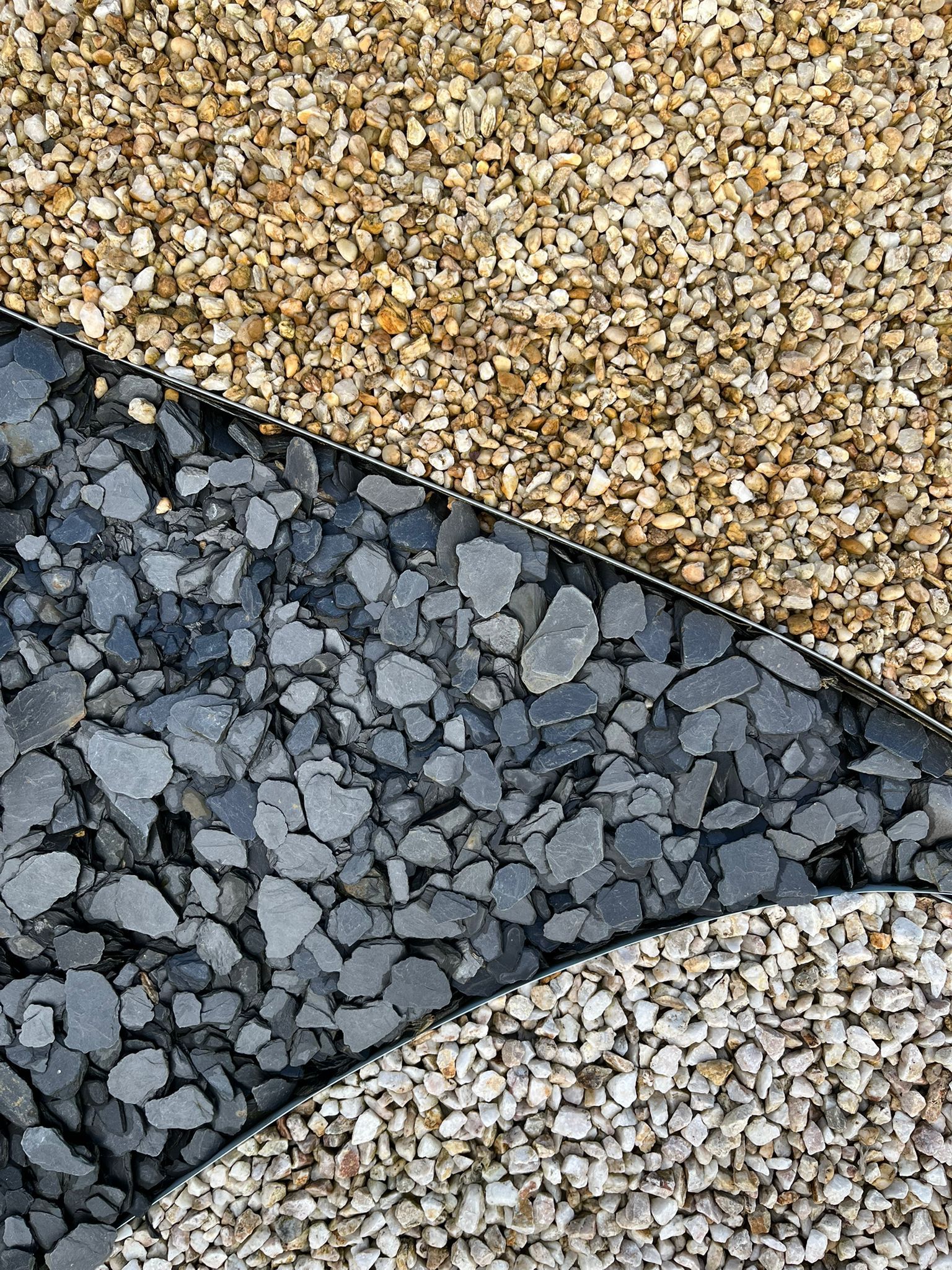 Gros plan sur trois bandes de gravier texturées de couleur beige, gris foncé et gris clair.