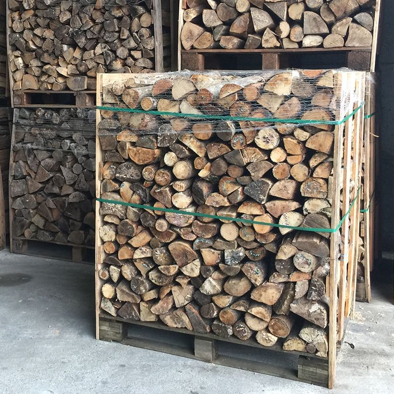Bois de chauffage empilé sur des palettes dans une zone de stockage
