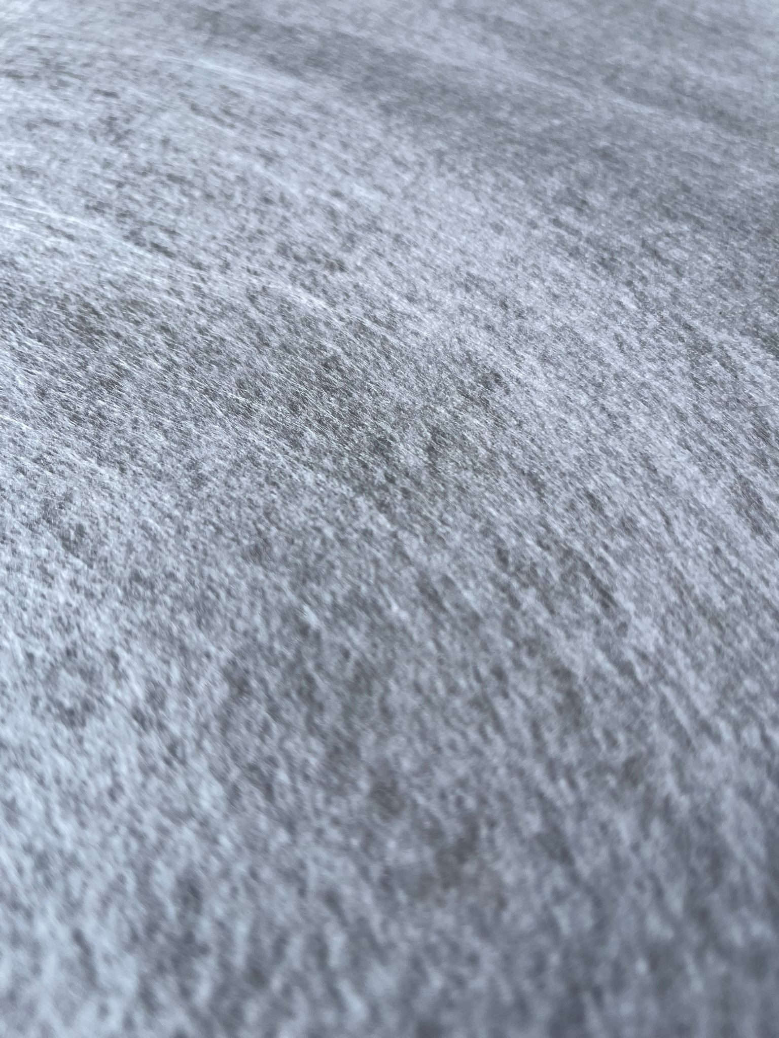 Tapis blanc enroulé, posé sur un sol en béton dans un espace intérieur sombre.