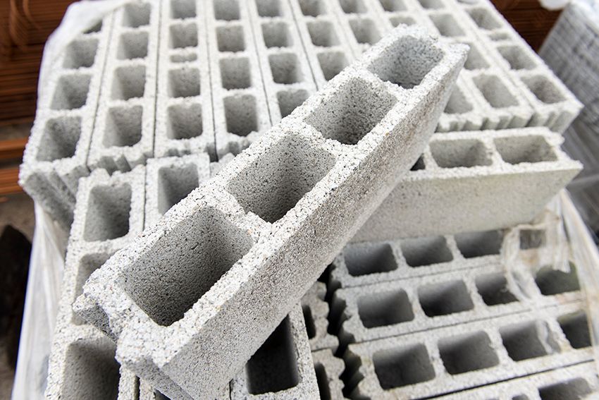 Blocs de béton gris empilés avec des noyaux creux sur une surface texturée