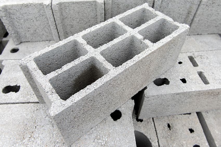 Blocs de béton gris empilés avec des noyaux creux sur une surface texturée