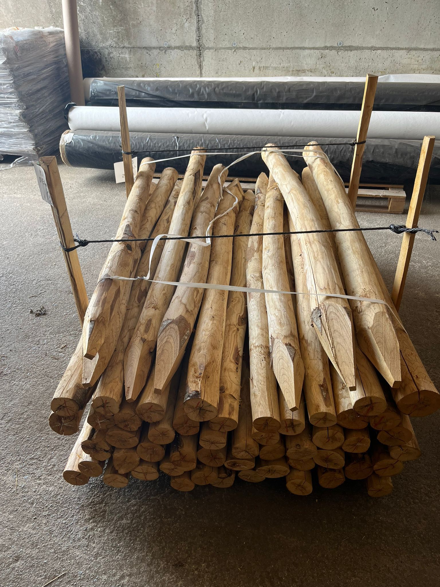 Des bûches et des branches coupées, empilées à l'extérieur sur une surface de gravier.