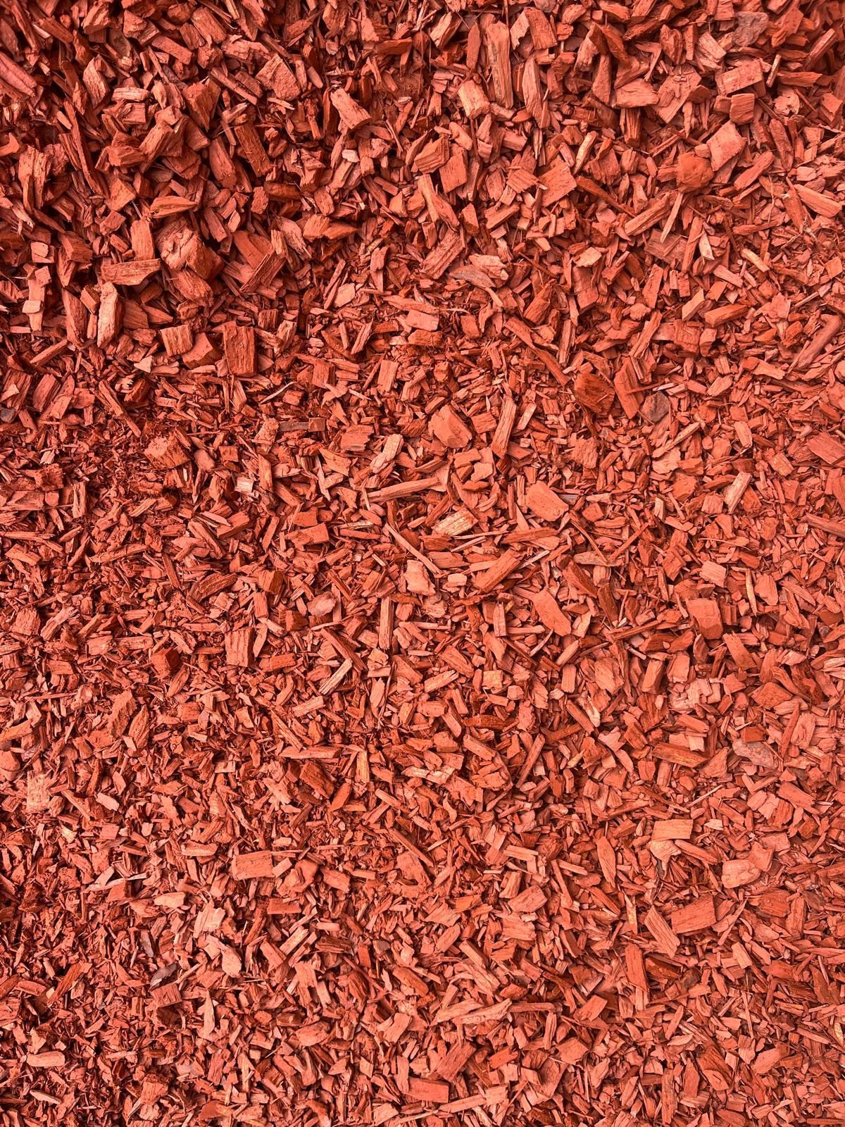 Ornement de jardin sphérique noir à côté d'un mur blanc dans un parterre de paillis rouge
