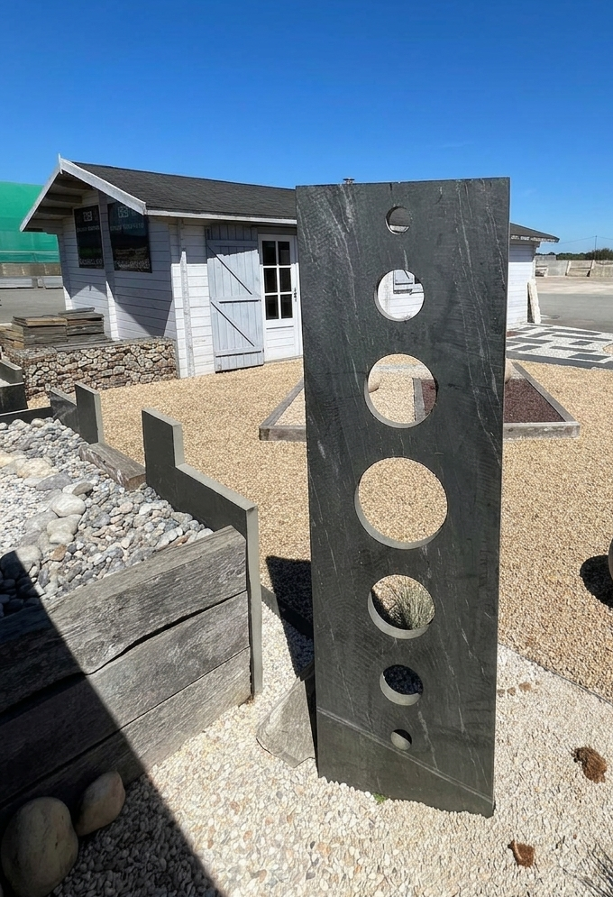 Sculpture contemporaine en plein air composée de hautes plaques grises ajourées de cercles