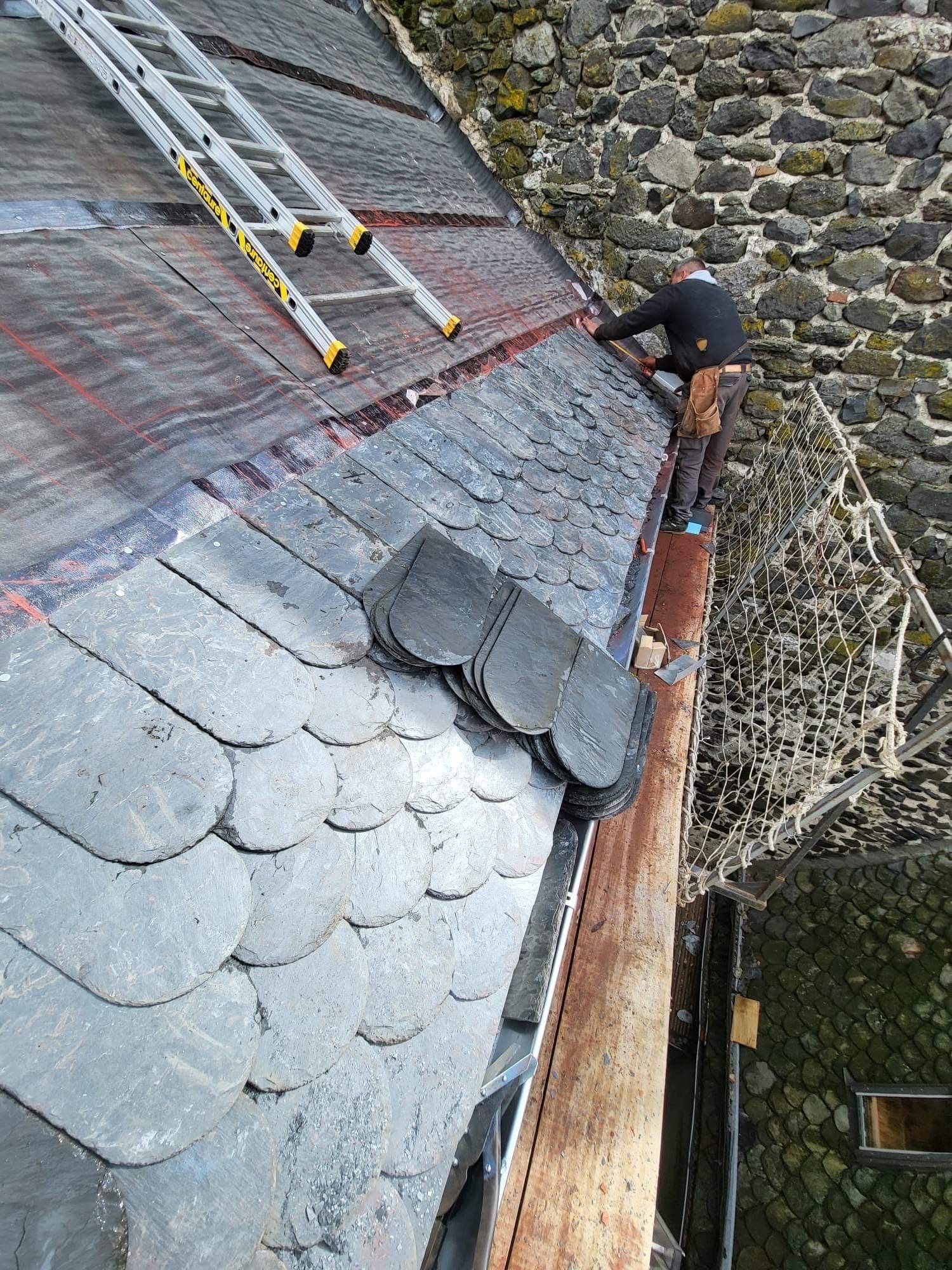 Un couvreur pose des ardoises sur une toiture