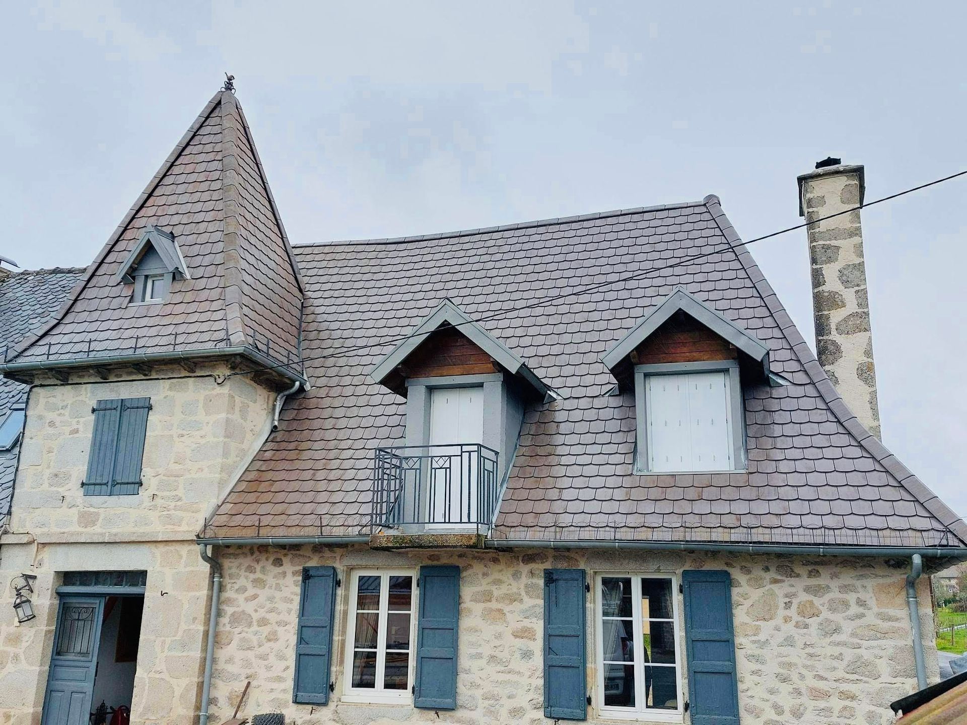 Toiture en ardoise rénovée avec un ciel gris