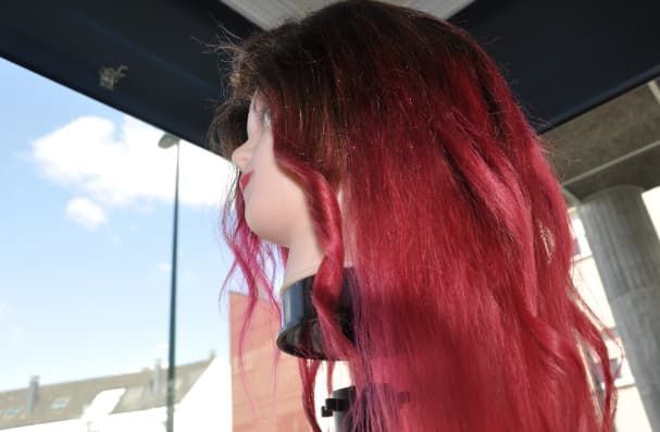 Cabeza de maniquí con cabello ombré de color rosa oscuro a brillante, mirando hacia una ventana.