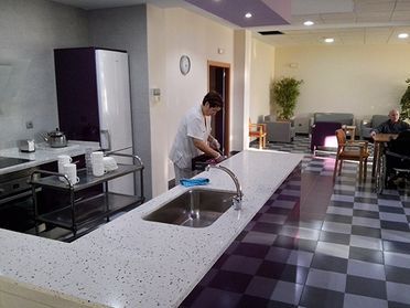 Un hombre está lavando platos en una cocina con suelo a cuadros.