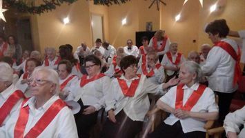 Un grupo de personas están sentadas en una habitación con fajas rojas.