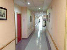 Un largo pasillo en un hospital con una puerta roja.