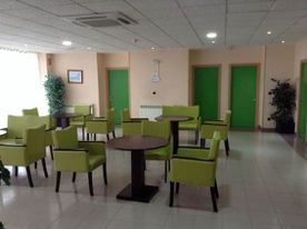 Una habitación con sillas y mesas verdes y puertas verdes.