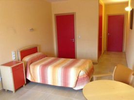 Un dormitorio con una cama, mesita de noche, silla y mesa.