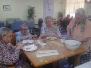 Un grupo de personas mayores están sentadas en una mesa comiendo comida.