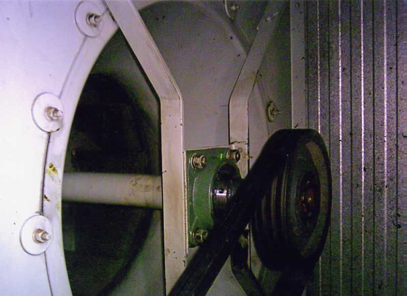 Aspas de ventilador y sistema de transmisión por correa dentro de una máquina industrial.