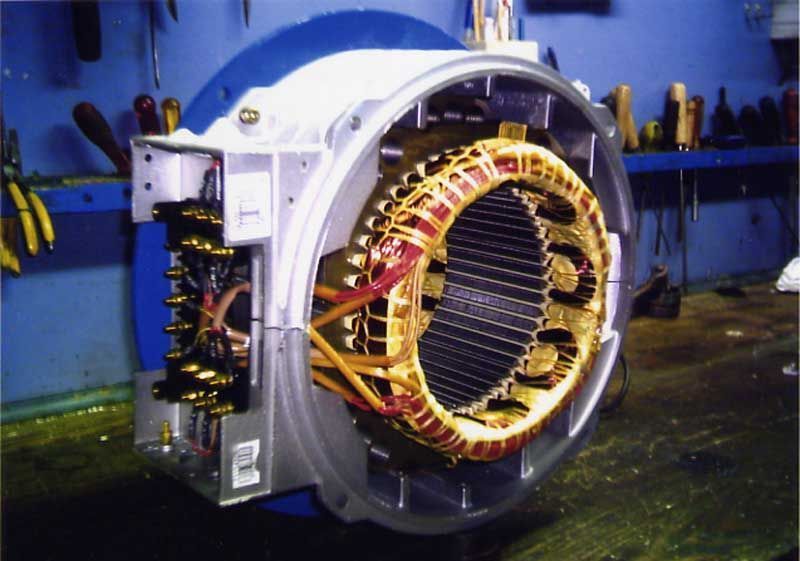 Motor eléctrico abierto con bobinados de cobre, visto desde un ángulo. Se ven los cables y la estructura metálica.