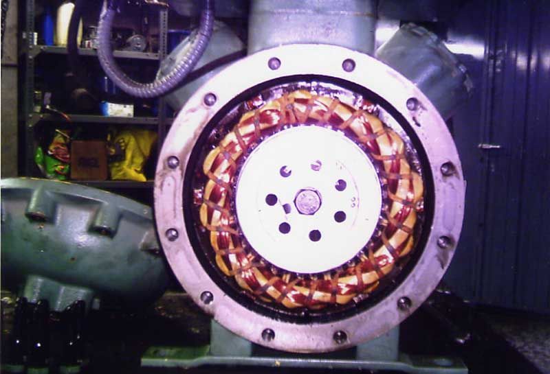 Estator de un motor industrial, con bobinados de cobre visibles dentro de un marco circular. Engaste metálico oscuro.