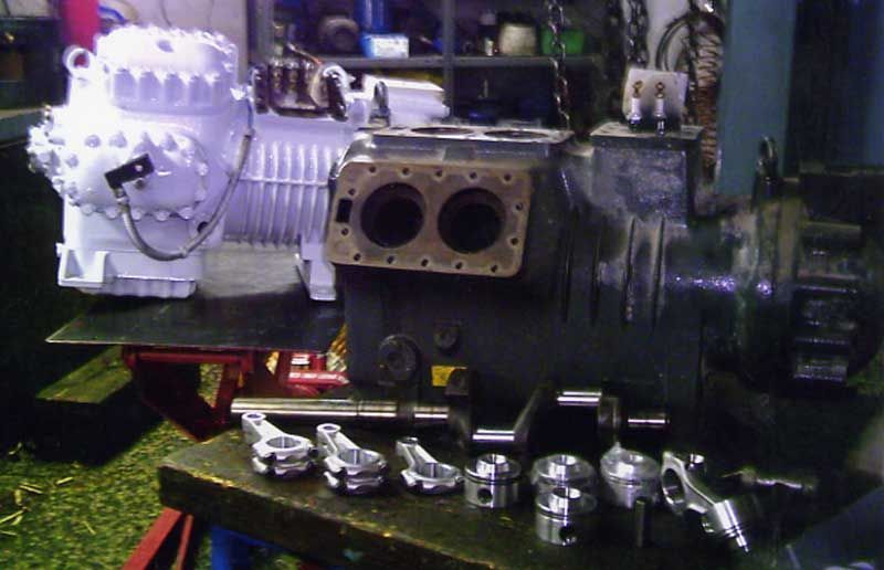 Compresor desmontado con componentes dispuestos sobre una mesa en un taller.