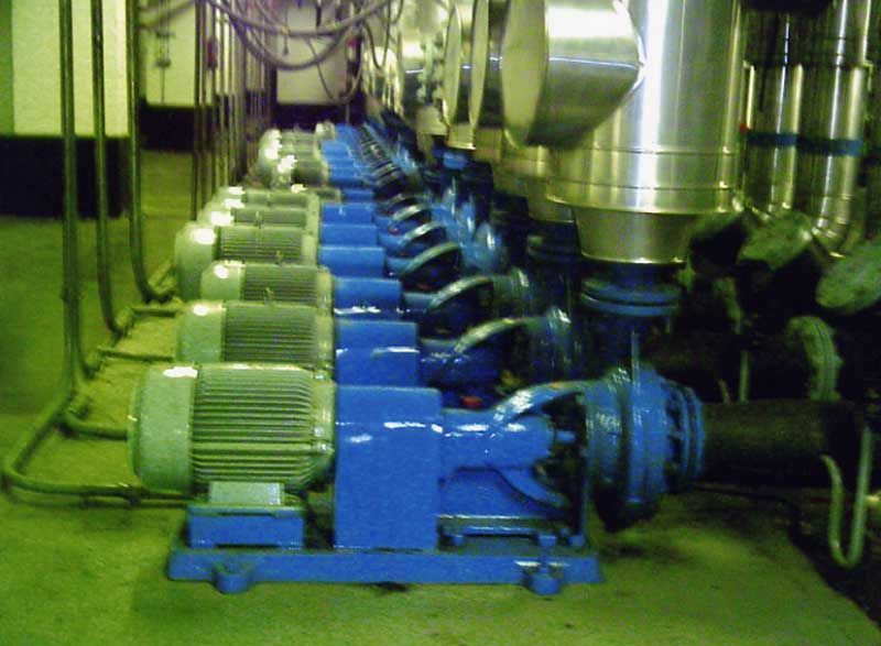 Fila de bombas industriales azules con tuberías y motores plateados.