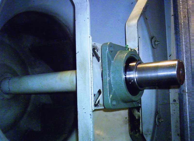 Un eje metálico con un cojinete, dentro de una estructura cilíndrica, posiblemente industrial.