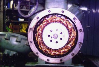 Vista abierta del interior de un motor eléctrico, mostrando devanados de cobre, placa blanca con agujeros, dentro de una carcasa de metal.