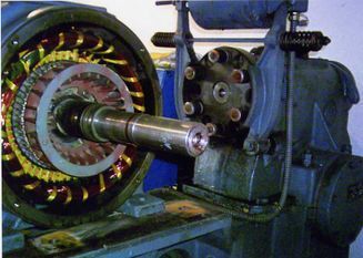 Un rotor de motor eléctrico en reparación en una máquina, mostrando los devanados y el eje.