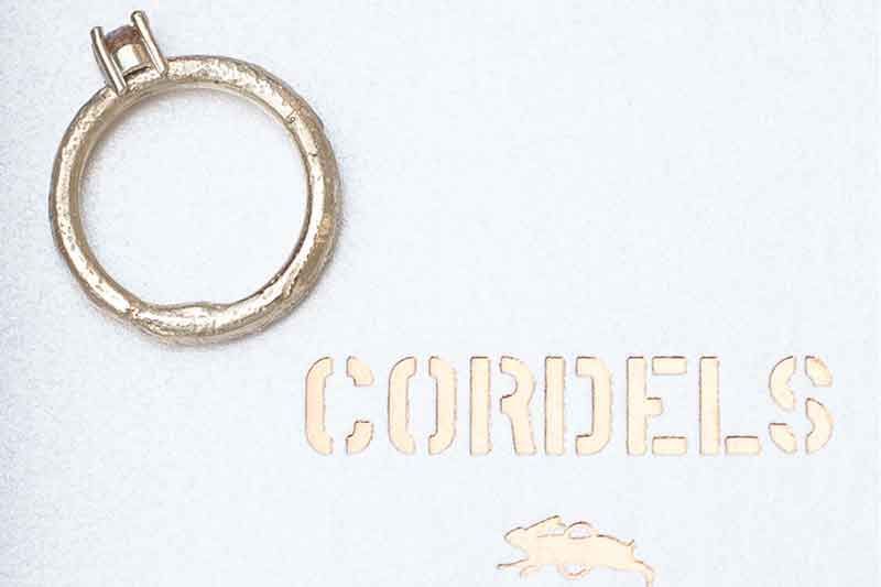 Goldring neben dem goldfarbenen Wort „CORIDELS“ auf weißem Untergrund.