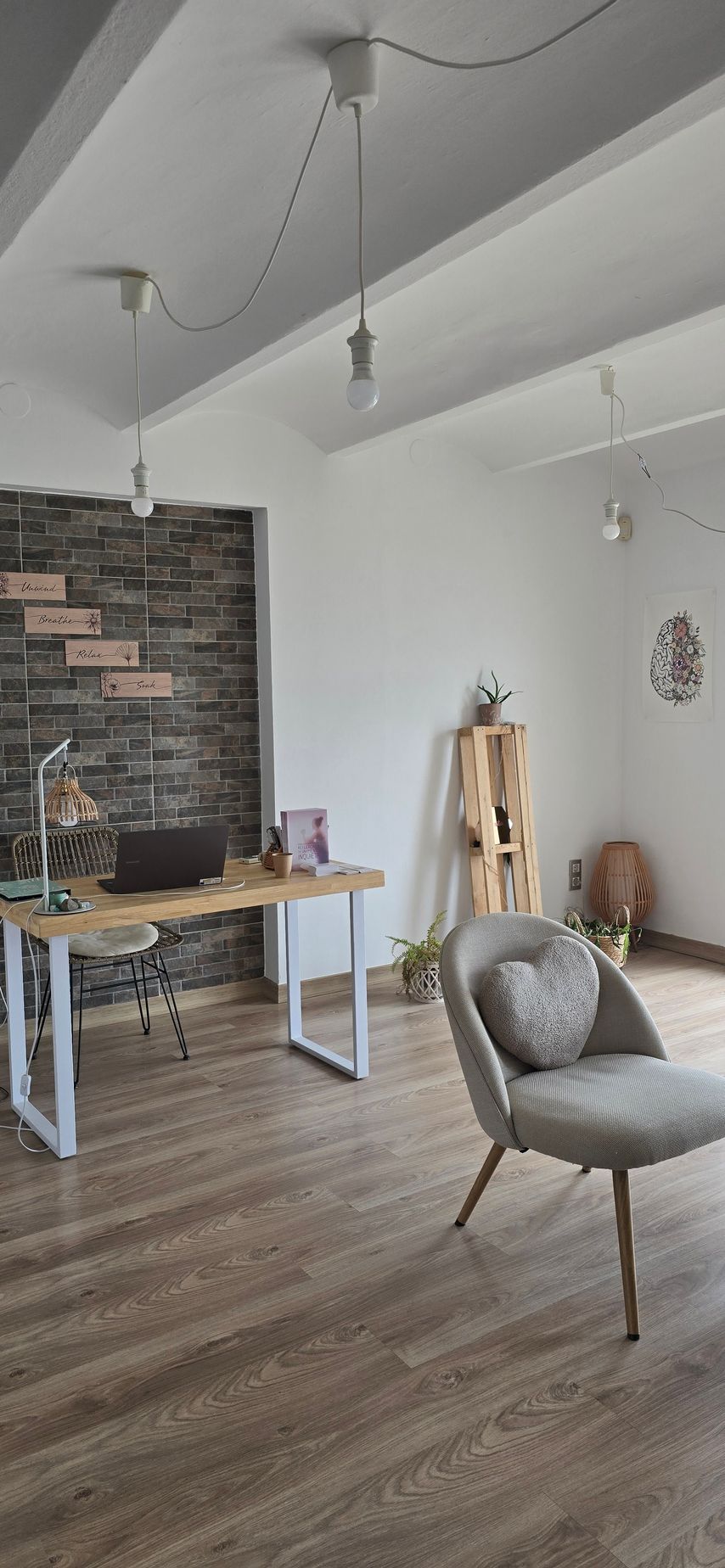 Una habitación acogedora con suelos de madera clara, tres sillas de mimbre, una mesita auxiliar y una ventana con reja metálica.