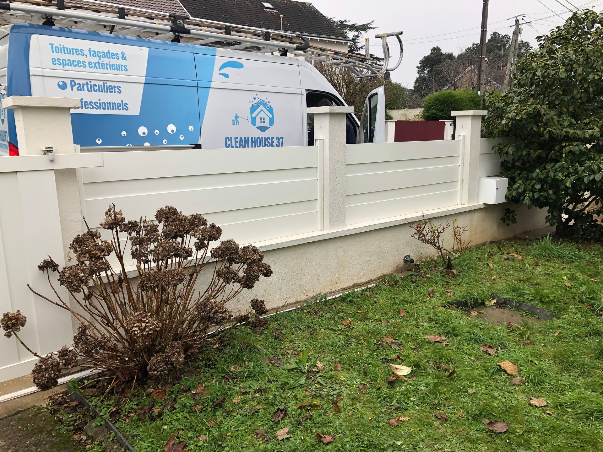 Véhicule de Clean House derrière un muret.