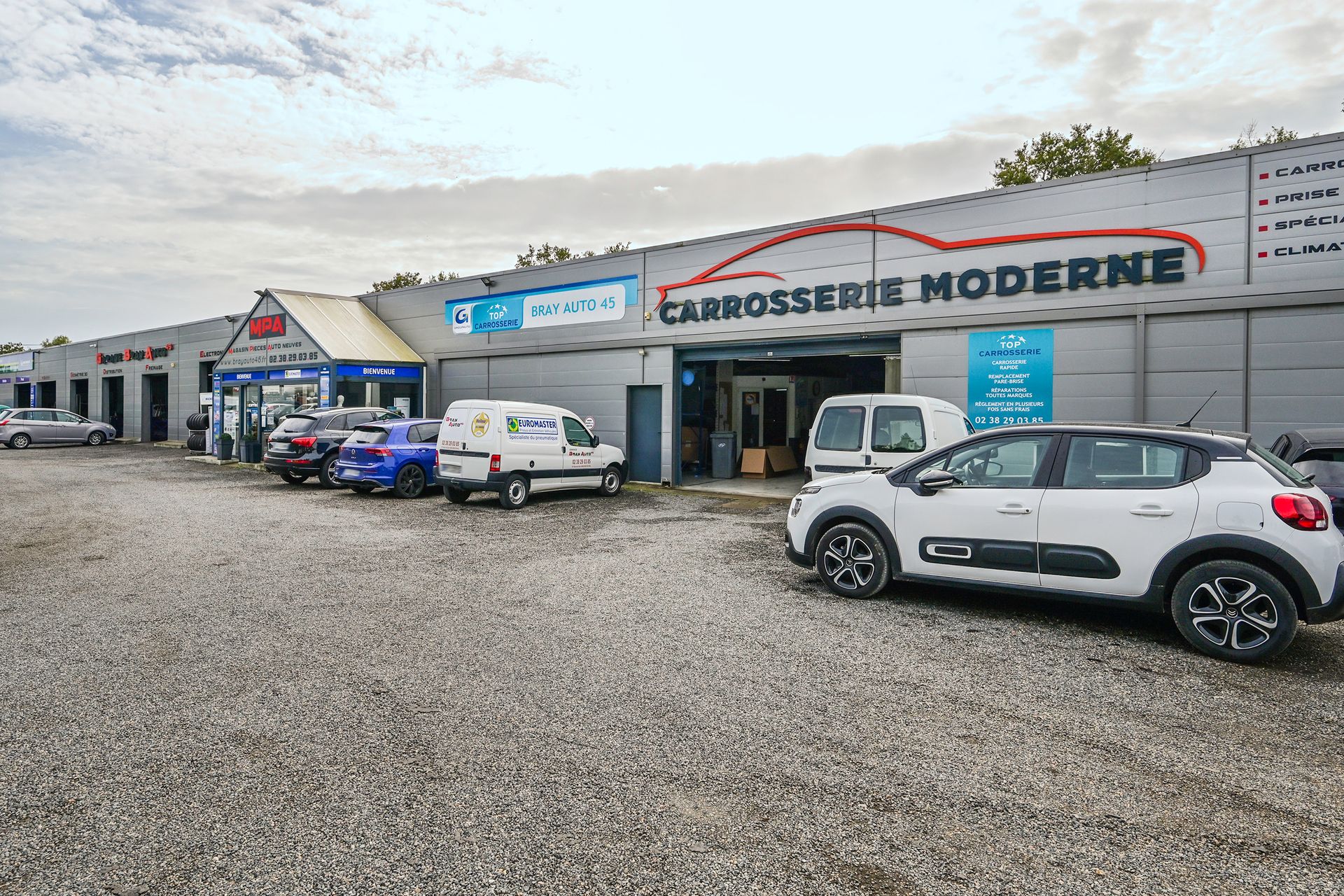 La devanture du garage automobile avec plusieurs voitures devant.