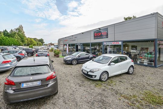 Plusieurs voitures en vente garées devant le garage.
