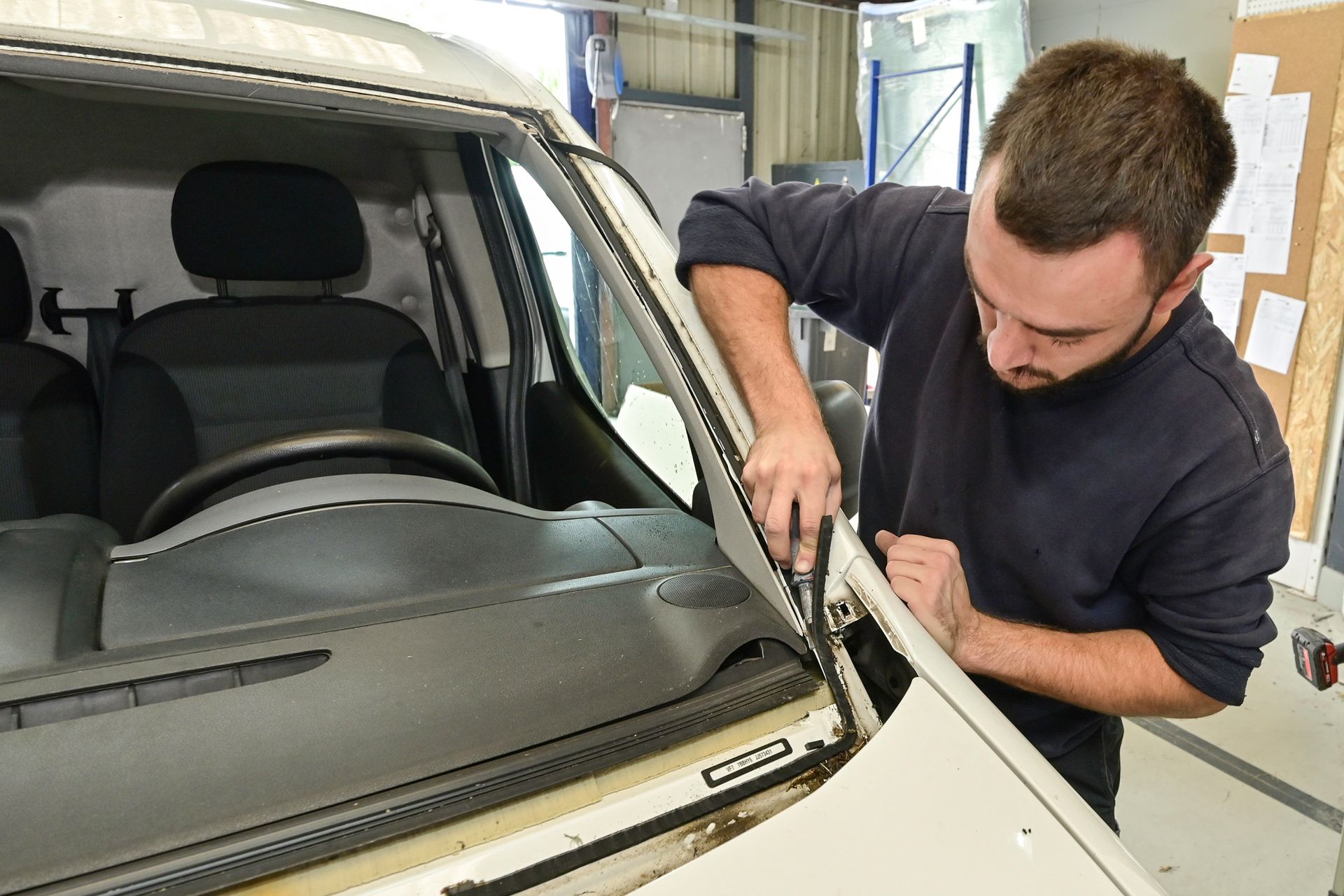 Un technicien en train de changer le joint d'un pare-brise.