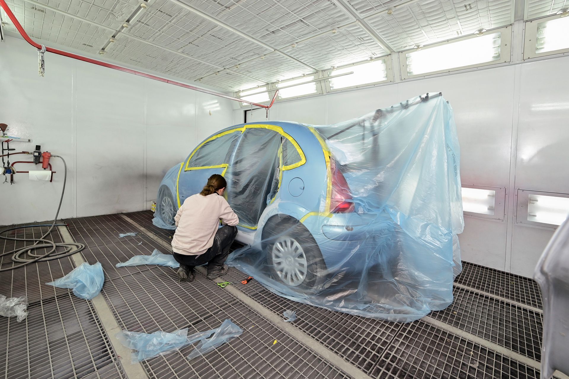 Une personne en train de réaliser la mise en peinture d'une voiture.
