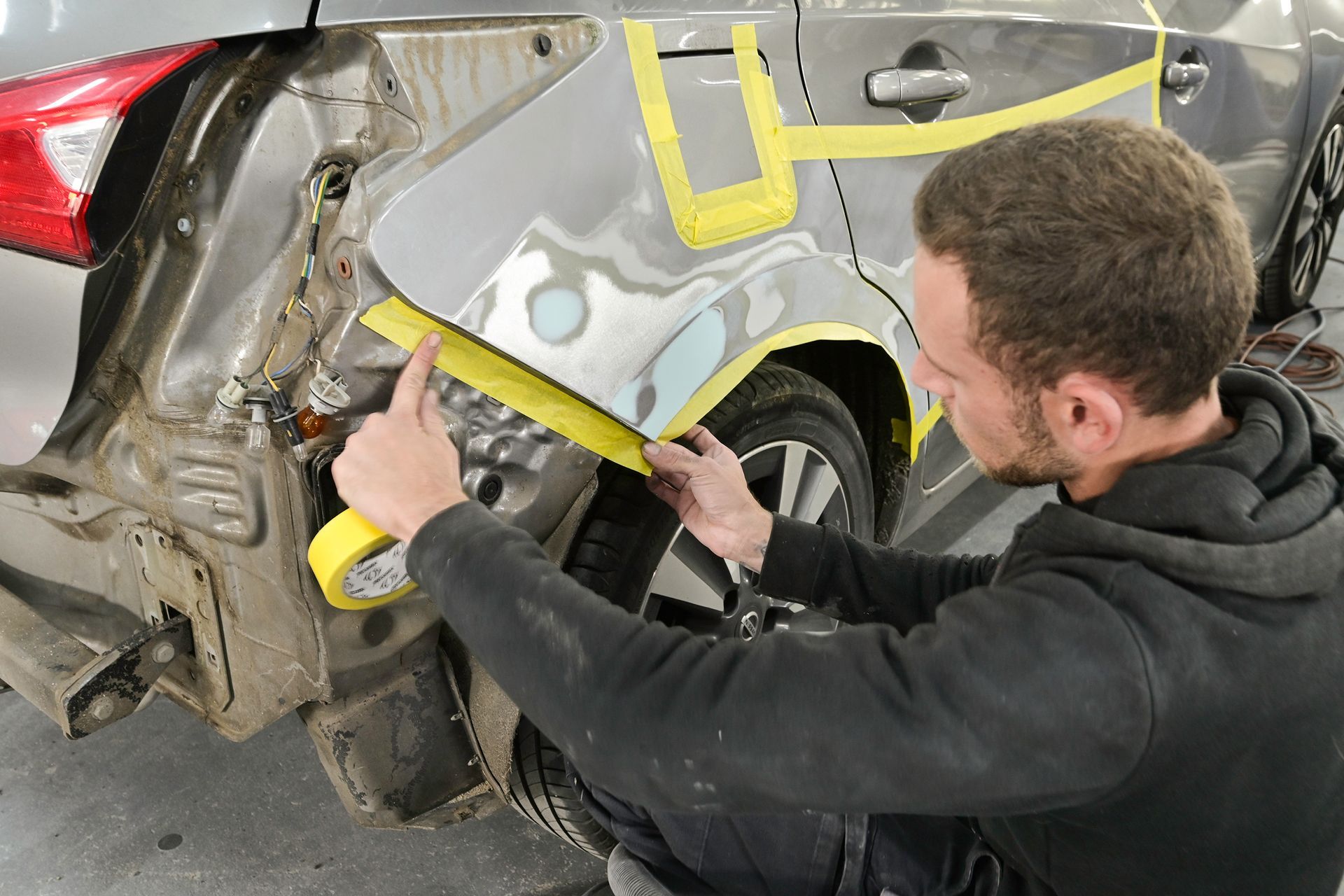 Gros plan sur le côté d'une voiture accidenté et un technicien à côté.