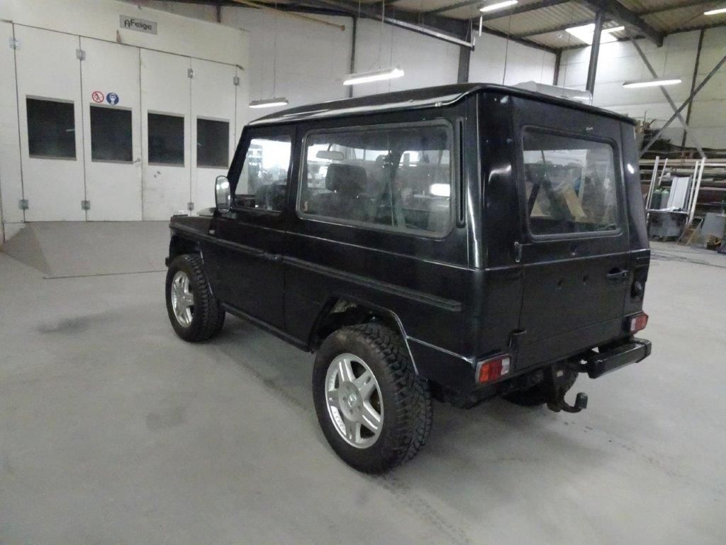 Ein Mann mit orangefarbenen Handschuhen arbeitet an einem Automotor.