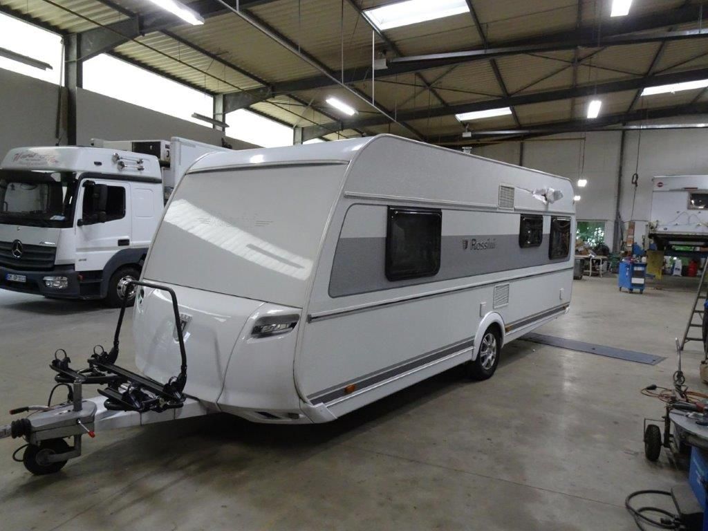 Ein Mann arbeitet mit einem Schraubenschlüssel an einem roten Auto.